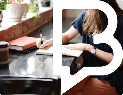 Person writing in a notebook at a desk.