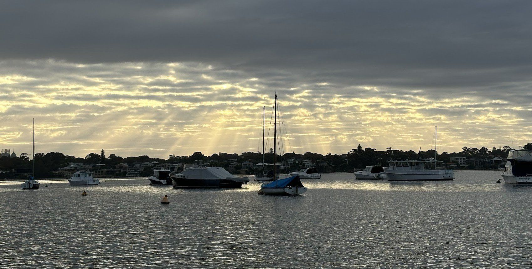 Boats docked on a calm water body under a cloudy sunrise sky.