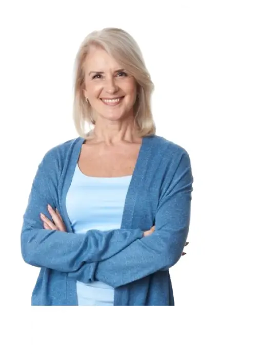 Smiling woman with blonde hair in a light blue top and cardigan, standing with arms crossed on a white letter B background